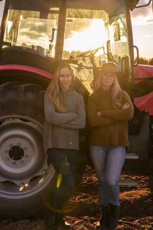 Two women farmers and harvester on cultivated fieldの写真素材