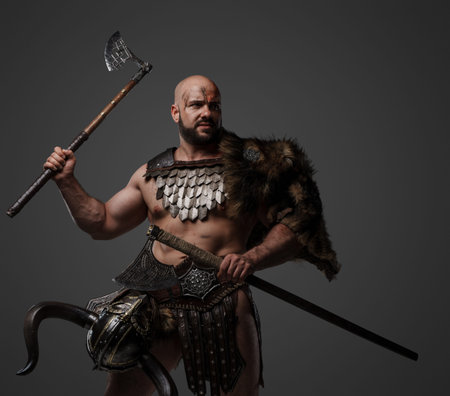 Handsome barbaric viking with axes against grey background