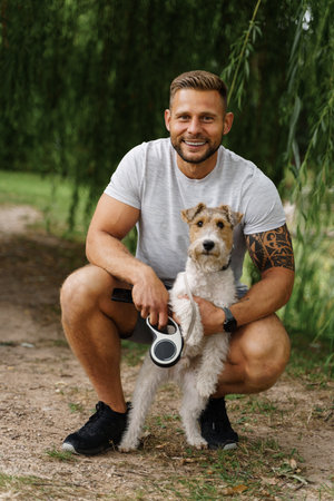 Tattooed man dog owner walking in sunny day at natureの写真素材