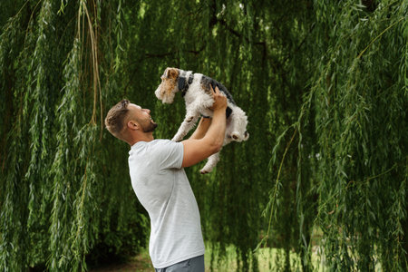 Cheerful man holding his dog outdoors at nature