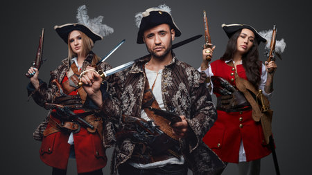 Handsome pirate with flintlock pistol and two female buccaneersの写真素材