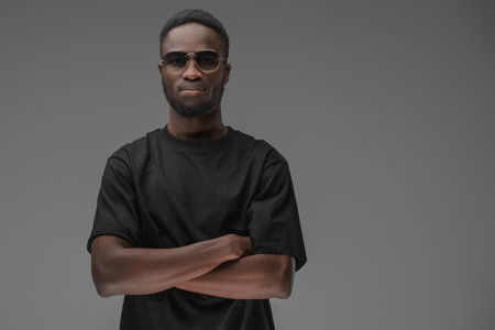 Confident african guy with black shirt against gray backgroundの写真素材