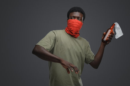 Aggressive african man throwing molotov coctail against gray background