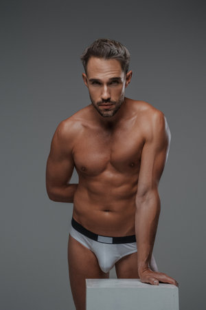 An attractive male model, dressed only in underwear on a gray backdropの写真素材