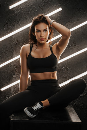 Toned woman in sportswea, vibrant lamps lighting the dark studioの写真素材