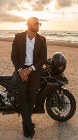 A luxuriously dressed man on his motorcycle amidst a serene beach at sunsetの写真素材