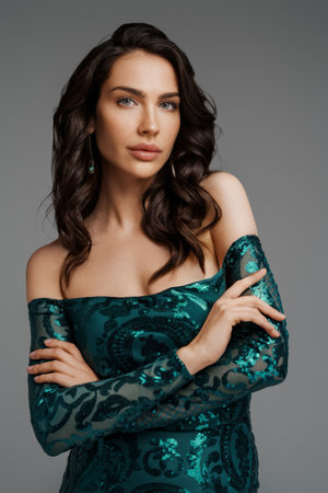 Stunning brunette in a graceful green evening gown against a gray backdropの写真素材