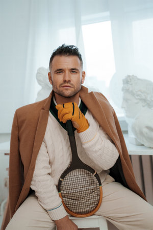 Stylish male model dressed in a vintage wealthy fashion with a tennis racketの写真素材