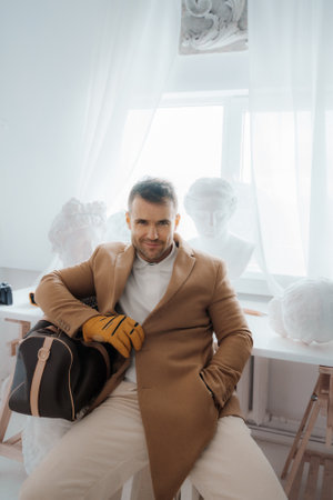 Old-money style man with a captivating smile holding a bag and tennis racketの写真素材