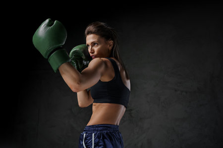 Female fighter in sports bra and boxing gloves showcases striking techniquesの写真素材