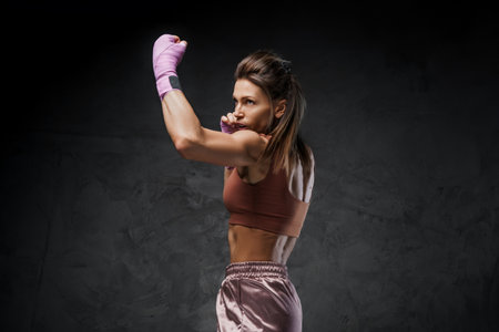 Athletic female fighter showcasing punch technique on a dark backgroundの写真素材