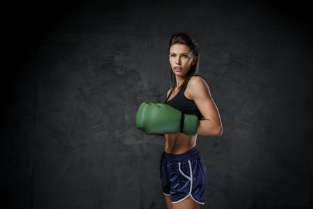 Female fighter in sports bra and boxing gloves showcases striking techniquesの写真素材