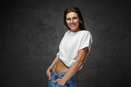 Striking female portrait in spectacles and white tee set against moody backdropの写真素材