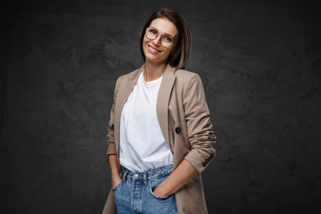 Beaming woman in eyewear, t-shirt, and jacket showcases her chic styleの写真素材