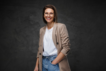 Beaming woman in eyewear, t-shirt, and jacket showcases her chic styleの写真素材