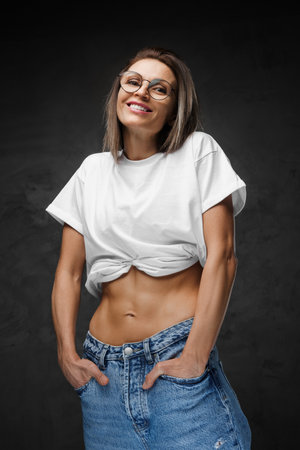 Woman smiles in eyewear, lifting her crop-top to spotlight a sculpted midriffの写真素材