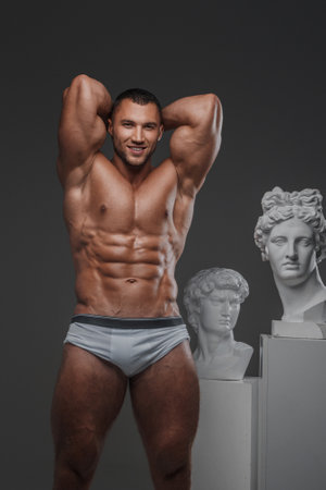 Smiling Rugged Man with Perfect Muscular Torso and Greek Statuesの写真素材