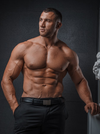 Stylish Man with Muscular Torso and Greek Statuesの写真素材