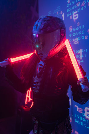 Woman in Futuristic Tactical Black Suit and Motorcycle Helmet with Neon Lampsの写真素材