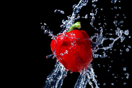 fresh red bell pepper gets hit by a water streamの写真素材