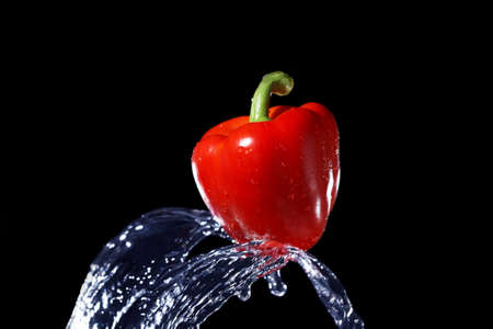 fresh red bell pepper gets hit by a water streamの写真素材