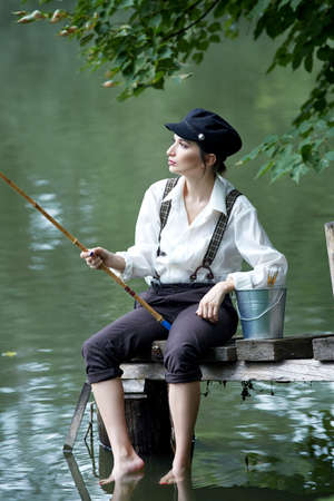Boyish looking girl fishing outdoors old schoolの写真素材