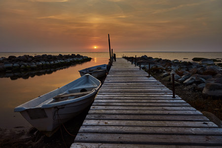 Beautiful sunset view with wooden jetty over sea and a boat