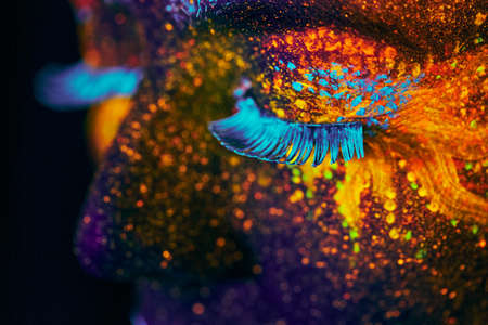 close up uv portrait glowing in a dark female modelの写真素材