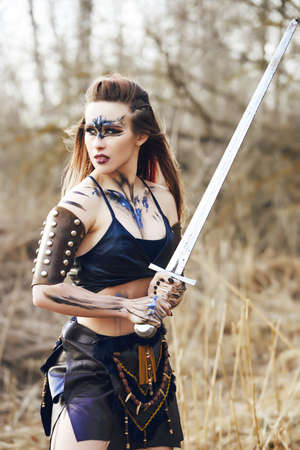 Beautiful amazon woman posing with sword late fallの写真素材