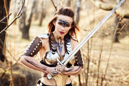Beautiful amazon woman posing with sword late fallの写真素材
