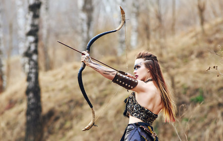 Beautiful amazon woman posing with bow late fallの写真素材