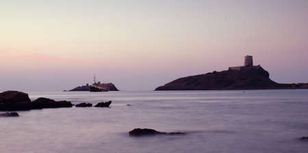 Sunrise in Sardinia with lighthouse and rocksの写真素材