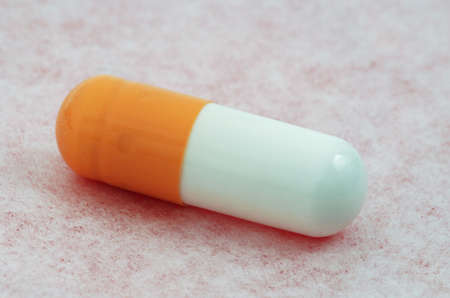 Single medical capsule macro isolated on the pink surfaceの写真素材