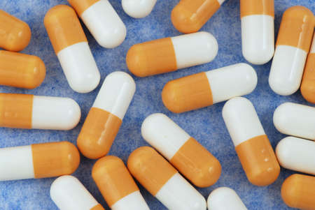 Yellow and white medical capsules isolated on the blue backgroundの写真素材