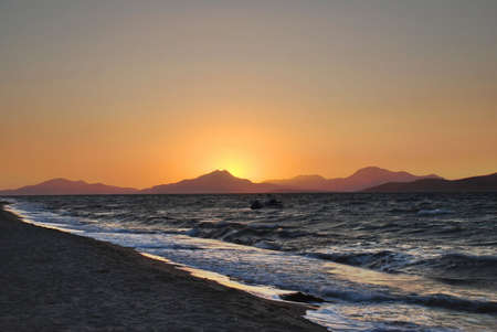Sun is setting behind the mountains and seaの写真素材