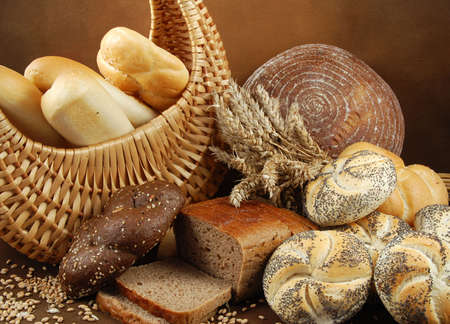 Various fresh crispy baked goods with a basket, wheat grain, poppy and a cereal earsの写真素材