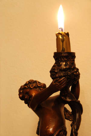 Statue of angel is holding a burning candle - christmas backgroundの写真素材