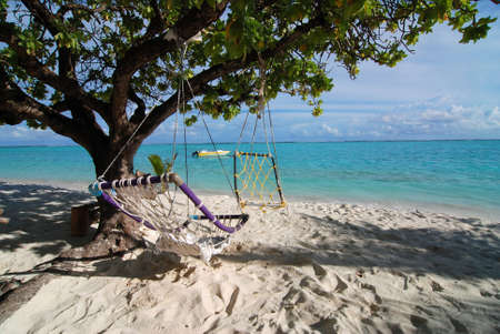 Two hammocks and tropical beach with azure sea in the backの写真素材