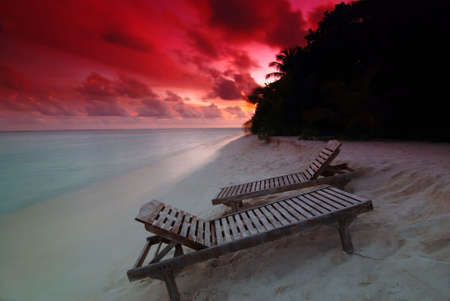 Two chairs on the Maldivian beach at beautiful sunsetの写真素材