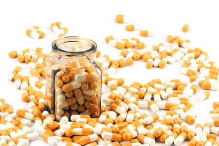 Glass jar with medical pills inside and outside isolated on whiteの写真素材