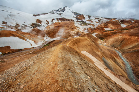 Iceland is a land of ice and fire. In the geothermal area Kerlingarfjoll one can see smoke and boiling fumaroles from the geothermal field as well as mountains covered by ice and snow.の写真素材