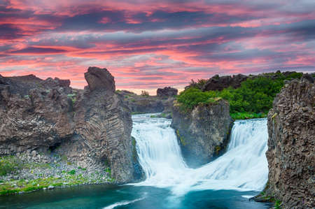 Double waterfall Hjalparfoss on the river Fossa after the midnight sunset with a beautiful vivid dramatic sky and basalt rocksの写真素材
