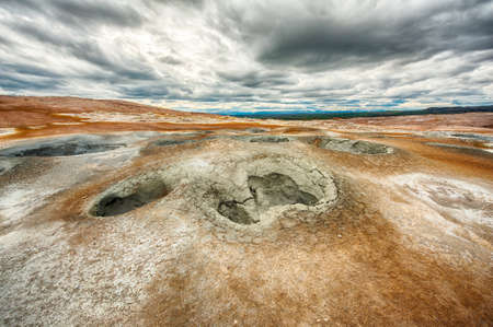 Mudpots in the geothermal area Hverir, Iceland. The area around the boiling mud is multicolored and cracked. HDR imageの写真素材