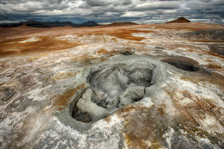 Mudpots in the geothermal area Hverir, Iceland. The area around the boiling mud is multicolored and cracked. HDR imageの写真素材