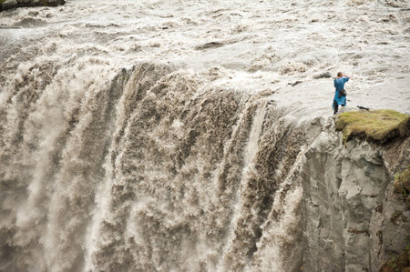 Unrecognizable photographer is taking pictures of Hafragilsfoss, very powerful waterfall. It is located in Jokulsargljufur National Park the northeasten Iceland on the river Jokulsa a Fjollum.の写真素材
