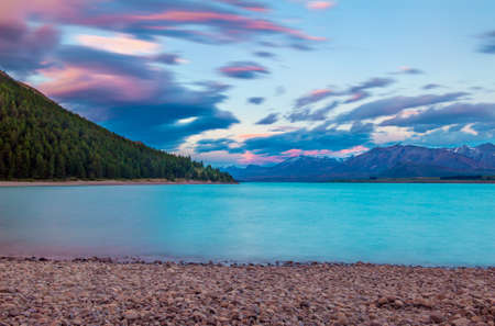 Beautiful dramatic sunset over the incredibly blue lake Tekapo with mountains, Southern Alps, on the horizon. New Zealandの写真素材