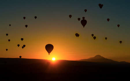 Silhouetts of hot balloons in morning sunrise and a mountain Erciyes. Cappadocia, Turkeyの写真素材