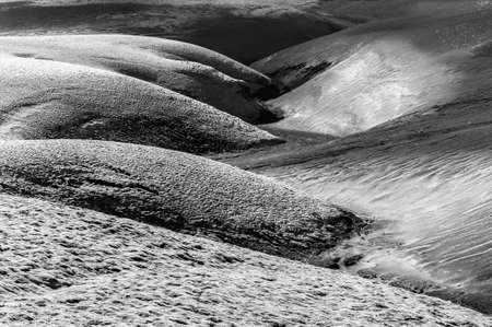 A contrasty wavy landscape of a former brook where black volcanic dunes meet dunes covered by moss. Lakagigar volcanic area, Iceland. Sunset time, monochromeの写真素材