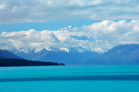 Mighty Mt. Cook is appearing from the clouds near the incredibly blue lake Pukaki at New Zealandの写真素材