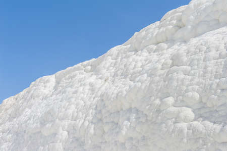 Pamukkale (cotton castle) natural wonder is created by a layers of white travertine looking like cotton, Turkey. Natural pamukkale wall against a blue skyの写真素材